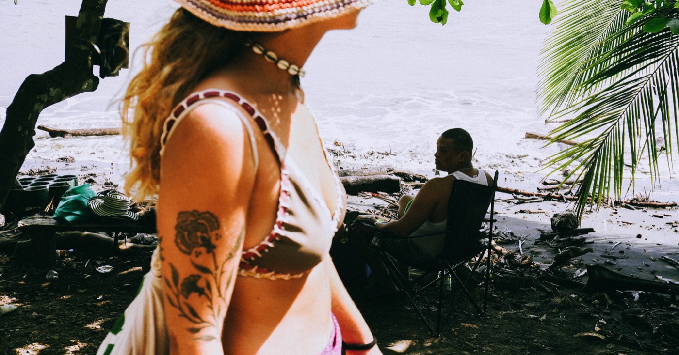 Mujer con sombrero de ganchillo en una playa con palmeras